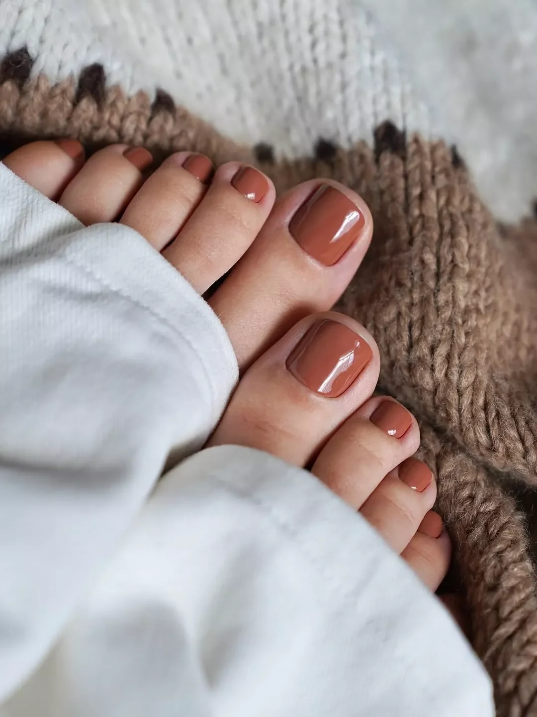 Карамельний педикюр із корицевим підтоном Карамельно-коричневий педикюр на осінь, обидві стопи на в'язаному пледі