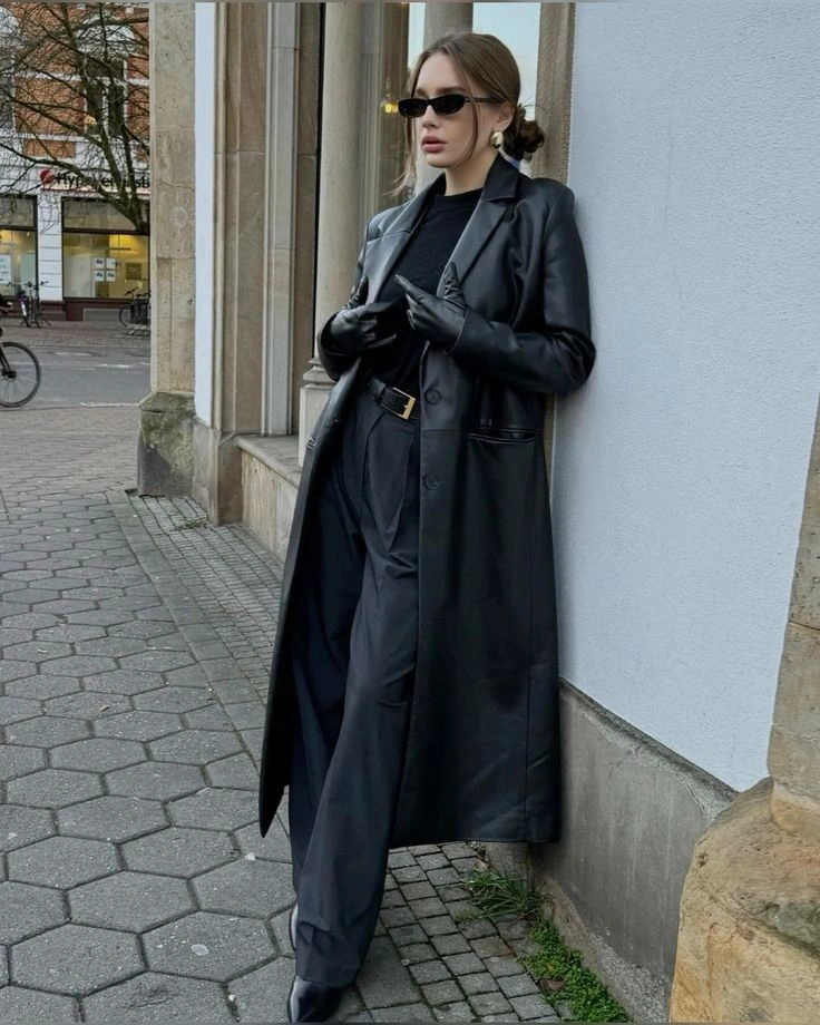Total black с кожаным плащом Женщина в чёрном кожаном плаще поверх футболки и прямых брюк